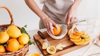 Frau drückt Grapefruit und Orangen aus