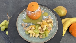 Schokoküchlein in der Orangenschale mit winterlichem Obstsalat