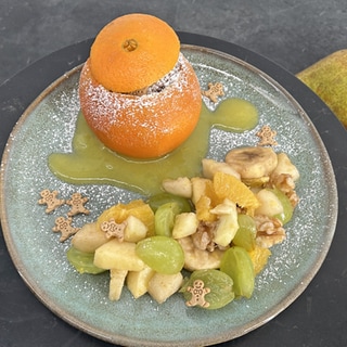 Schokoküchlein in der Orangenschale mit winterlichem Obstsalat