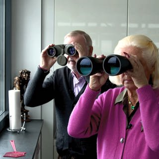 Klaus und Jutta Greinert schauen mit Ferngläsern aus ihrer Penthouse-Wohnung in einem Bunker in Mannheim