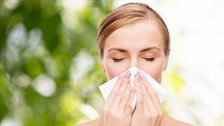 Heuschnupfen - Frau putzt sich die Nase