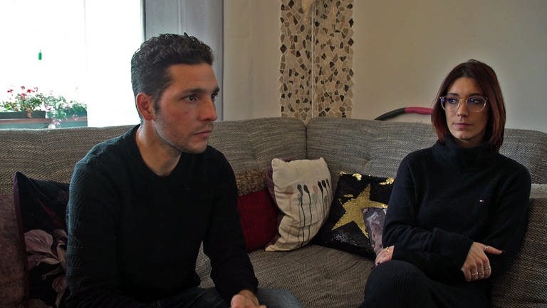 Maurizio Iannone und Carmela Saggio erzählen von ihrer verzweifelten Suche nach einem Kinderarzt. Sie sitzen nebeneinander auf der Couch.
