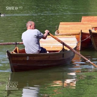 Mann fährt in einem Paddelboot über einen See