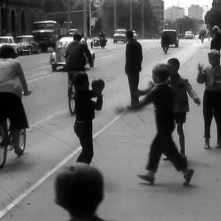 Schwarz-weiß-Bild: Kinder spielen mit einem Ball auf der Straße