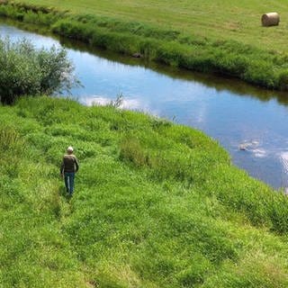 Donau-Experte Walter Knittel von Donaubergland GmbH läuft über eine Wiese zur Donau