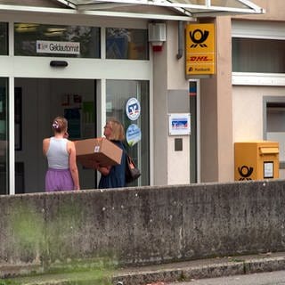 Zwei Frauen mit einemPaket stehen an der Tür der Post-Agentur in Blaustein