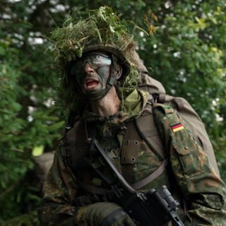 Rekrut steht bei einer Heimatschutz-Übung in Bundeswehr-Uniform im Wald