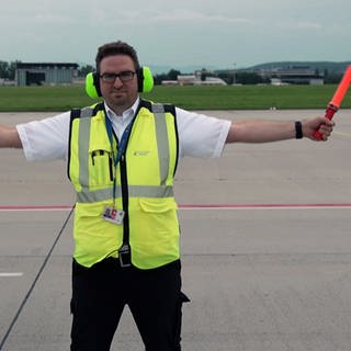 Daniel Günter ist Duty Airport Manager am Flughafen Stuttgart. er steht auf dem Rollfeld und weist ein Flugzeug ein.