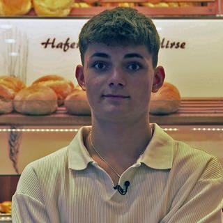 Linus Baur steht in einer Bäckerei. Er hat die Brötchenrutsche erfunden.