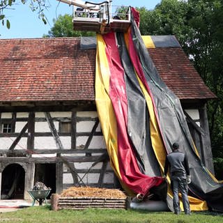 Freilichtmuseum in Neuhausen ob Eck wird mit einer Deutschlandflagge verhüllt, um die Holzwürmer zu bekämpfen.