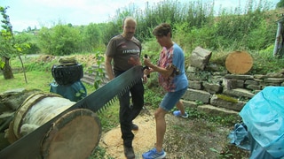 Markus Dengler, der Macher des Holzfällerwettbewerbs in Widdern sägt gemeinsam mit der Landesschau-Reporterin Sonja an einem Baumstamm.