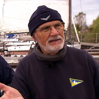 Regatta auf dem Kollersee: Kurt Magin von den Kollerskippern in Brühl steht auf einem Segelboot. 