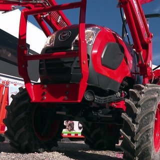 Ein Mann mit Warnweste steht neben einem roten Traktor auf der Oberschwabenschau in Ravensburg.