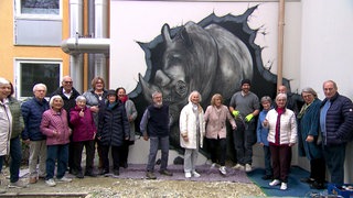 Senioren stehen vor einem Nashorn-Graffiti vor ihrem Seniorenheim in Überlingen