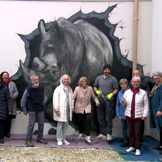 Senioren stehen vor einem Nashorn-Graffiti vor ihrem Seniorenheim in Überlingen