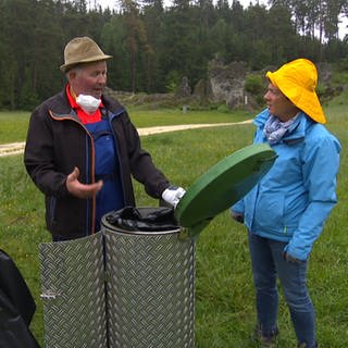 Mann leert Mülleimer im Wental