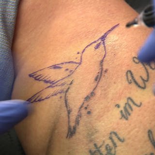 Ein Tattoo in Form eines Kolibris wird gestochen