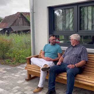 Daniel Müller und Rainer Schwab unterhalten sich auf einer Bank