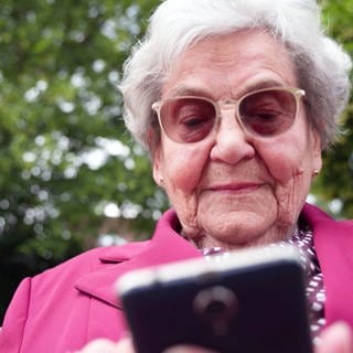Helga Dörhöfer beschäftigt sich mit ihrem Handy