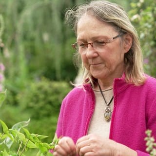 Astrid Weber lächelt versonnen in ihrem Heilkräuter-Garten
