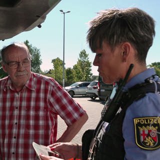 Polizistin kontrolliert ein Auto und einen älteren Fahrer