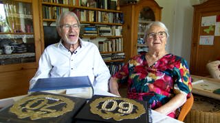 Klaus und Ruth Kallauch sitzen nebeneinander und lachen in die Kamera.