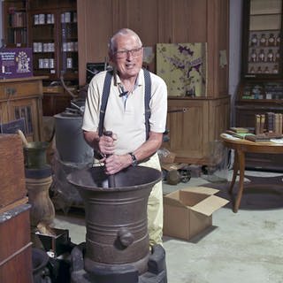 Bernd Schuffenhausen in seiner Apothekensammlung mit einem der größten Mörser, die es gibt