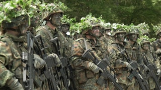 Angehende Soldaten in voller Tarnmontur und mit Waffe bei der Reservistenausbildung.