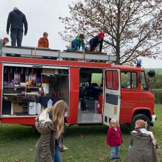 Kinder spielen um ein ausrangiertes Feuerwehrauto