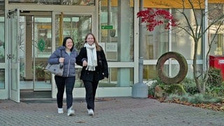 Mutter Petra mit ihrer Tochter Antonia verlassen ihre Arbeitsstätte.