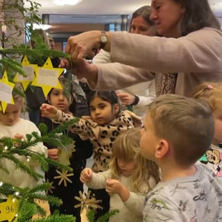 Kinder hängen Wünsche an Christbaum