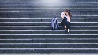 Verzweifeltes Mädchen sitzt auf einer Treppe