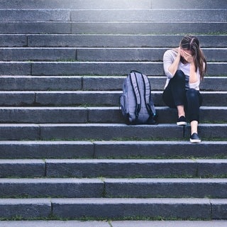 Verzweifeltes Mädchen sitzt auf einer Treppe