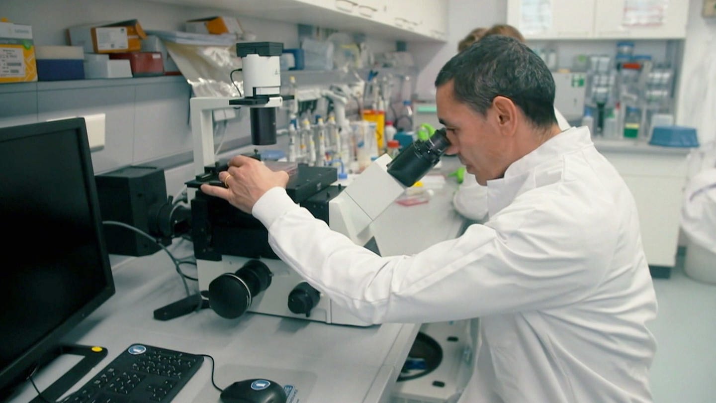 BioTech Gründer Ugur Sahin blickt in ein Mikroskop