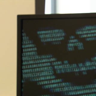 Mann im Profil sichtbar schaut auf Computer-Monitor mit einer Totenkopf-Darstellung