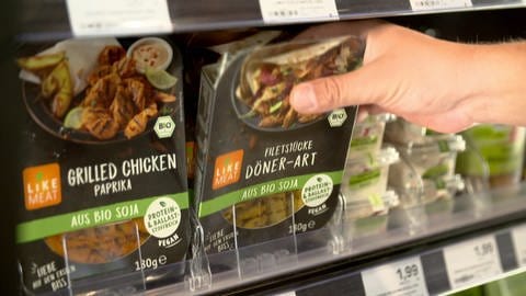 Kunde greift zum Fleischersatzprodukt in einer Supermarkt-Kühltheke