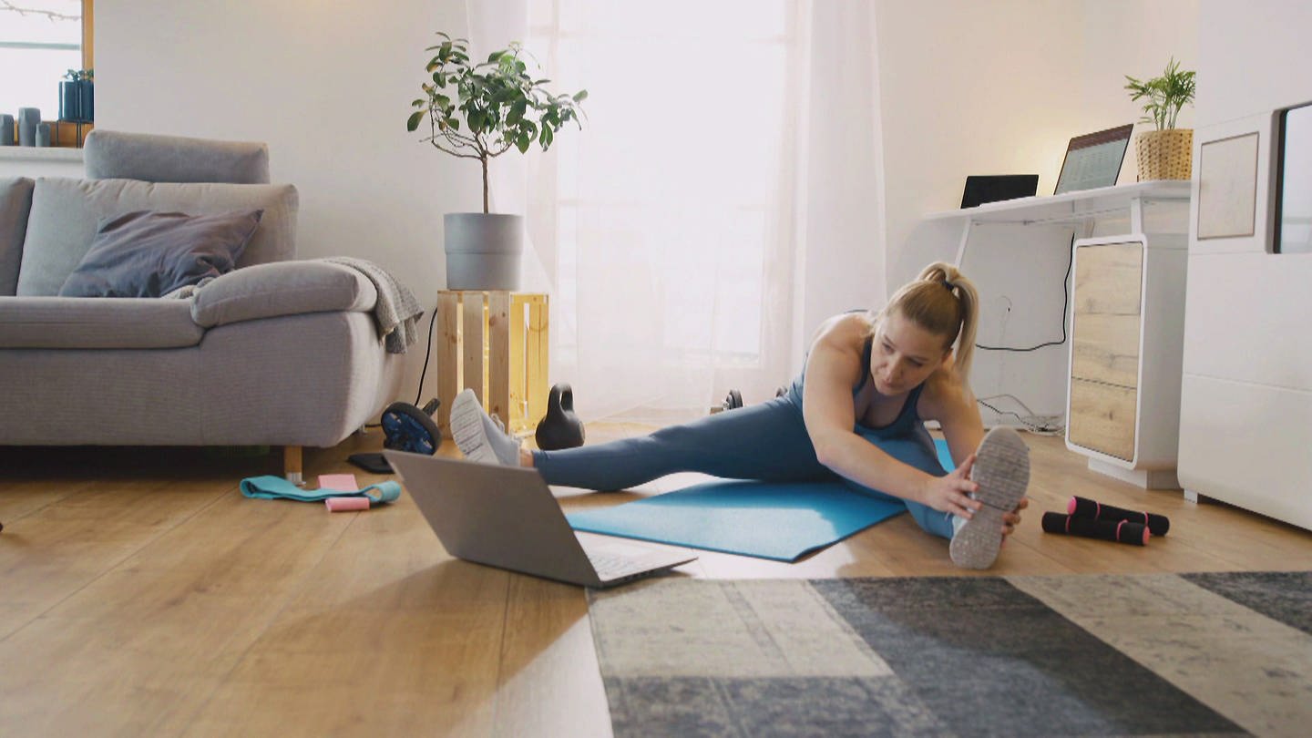 Online-Fitness: Frau folgt Workout-Anweisungen am Laptop-Display