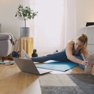 Online-Fitness: Frau folgt Workout-Anweisungen am Laptop-Display