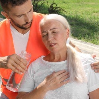 Mann reicht einer Frau eine Trinkflasche