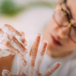 Frau inspiziert ihre Finger beim Händewaschen