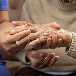 Eine junge Person hält eine gichtkranke Hand