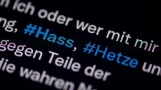 Auf dem Bildschirm eines Smartphones sieht man die Hashtags Hass und Hetze in einem Twitter-Post.