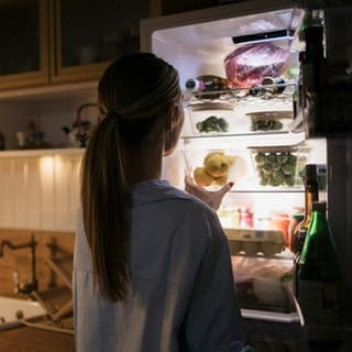 Frau geht nachts an den Kühlschrank