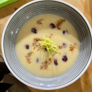 Selleriecremesuppe mit Kirschen, salzigem Walnusskaramell und Lauchstroh.