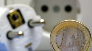 Eine Ein-Euro-Münze neben einer Steckdose und einem Stecker