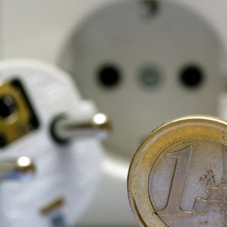 Eine Ein-Euro-Münze neben einer Steckdose und einem Stecker