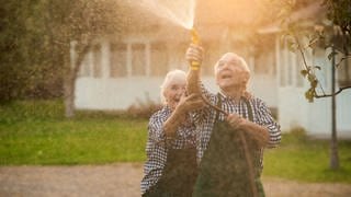 Älteres Paar albert mit Wasserschlauch herum