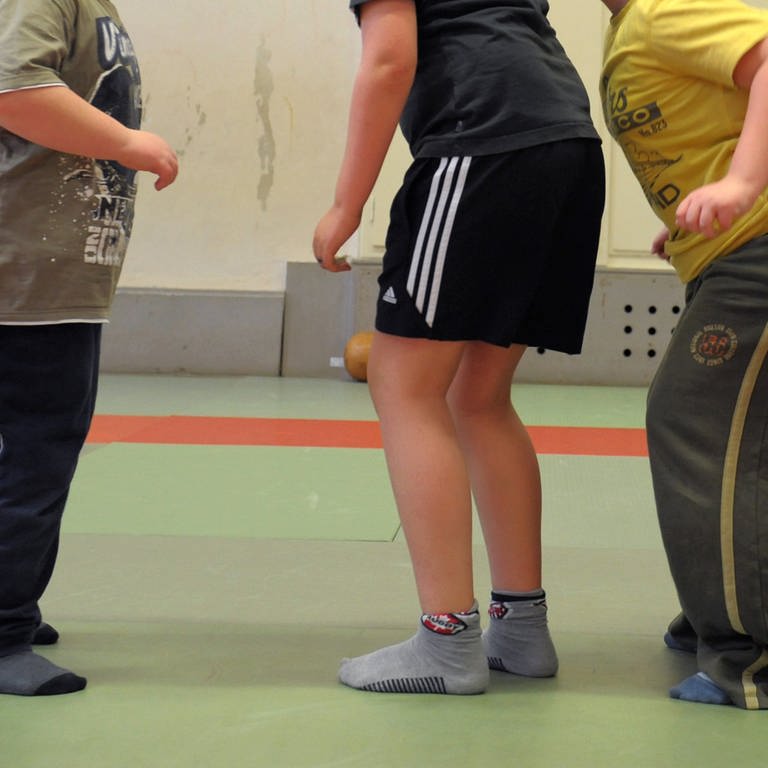 Kinder mit Übergewicht setzen in einer Sporthalle zum Sprung an