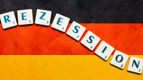 Auf einer Deutschlandfahne befinden sich die Scrabble-Buchstaben für das Wort Rezession.