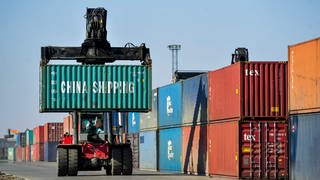 Ein Mann rangiert Container aus China für die Weiterverladung in einer Logistikstation.